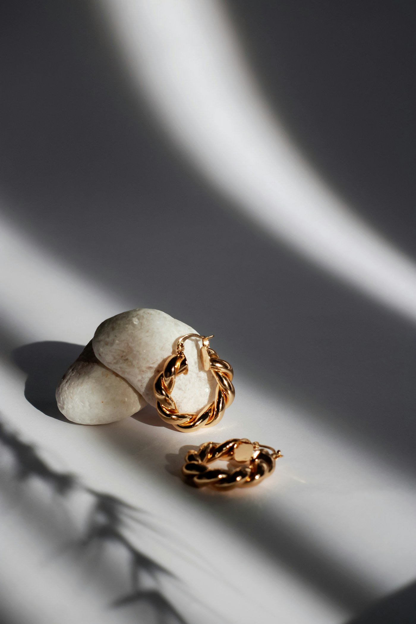 Gold hoop earrings arranged with fine chain jewelry on a pale surface