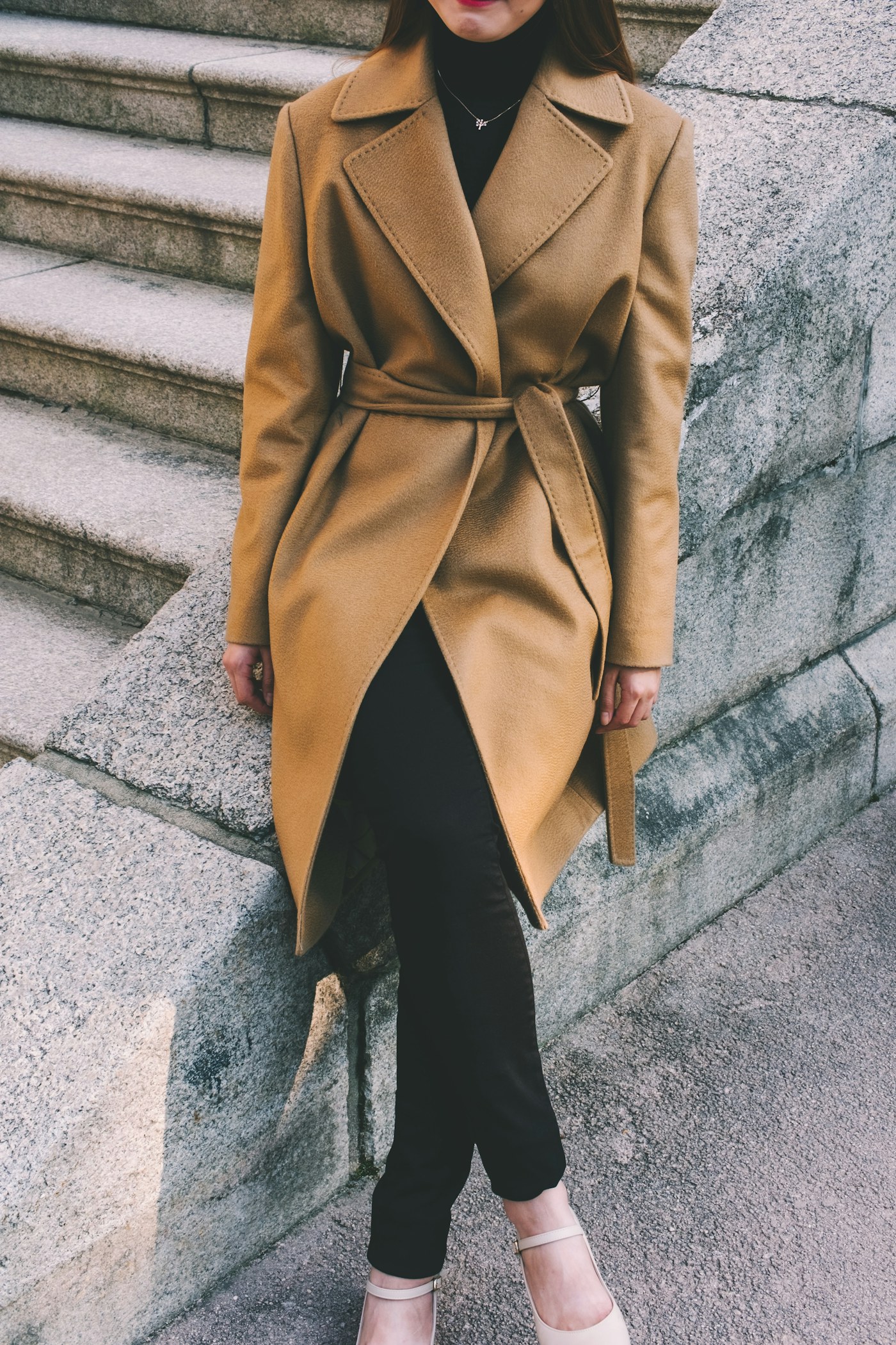 Woman in a warm winter coat walking through a city park on a cold clear day
